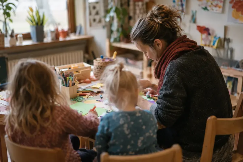 Eine Erzieherin bastelt mit zwei Kindern